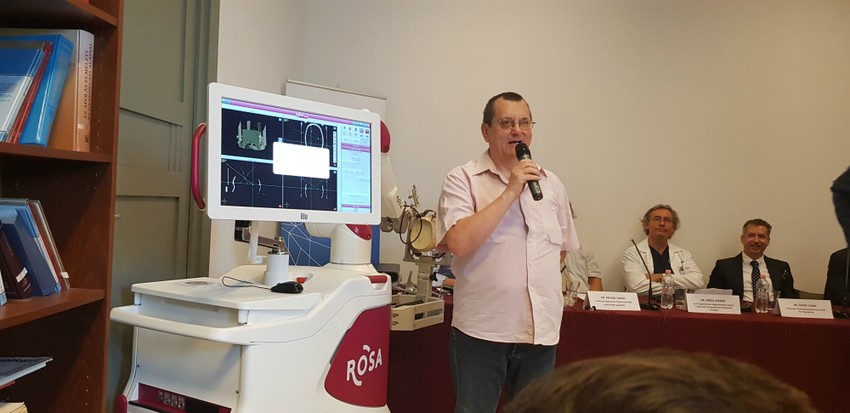 Onger György, az első magyarországi páciens válaszol a kérdésekre a ROSA nevű robot mellett.