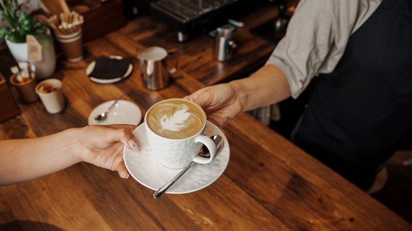 A,Barista,Hands,Over,A,Beautifully,Crafted,Cappuccino,With,Latte