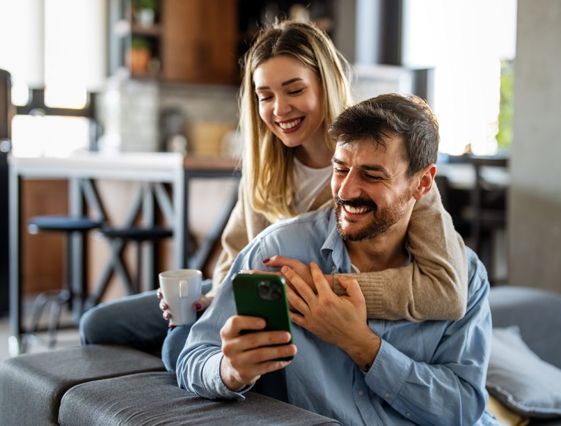 Smiling,Couple,Embracing,While,Looking,At,Smartphone.,People,Sharing,Social