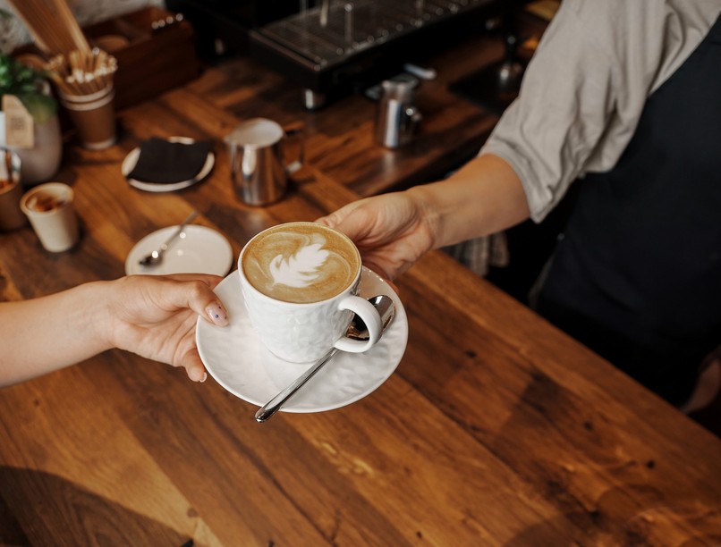 A,Barista,Hands,Over,A,Beautifully,Crafted,Cappuccino,With,Latte